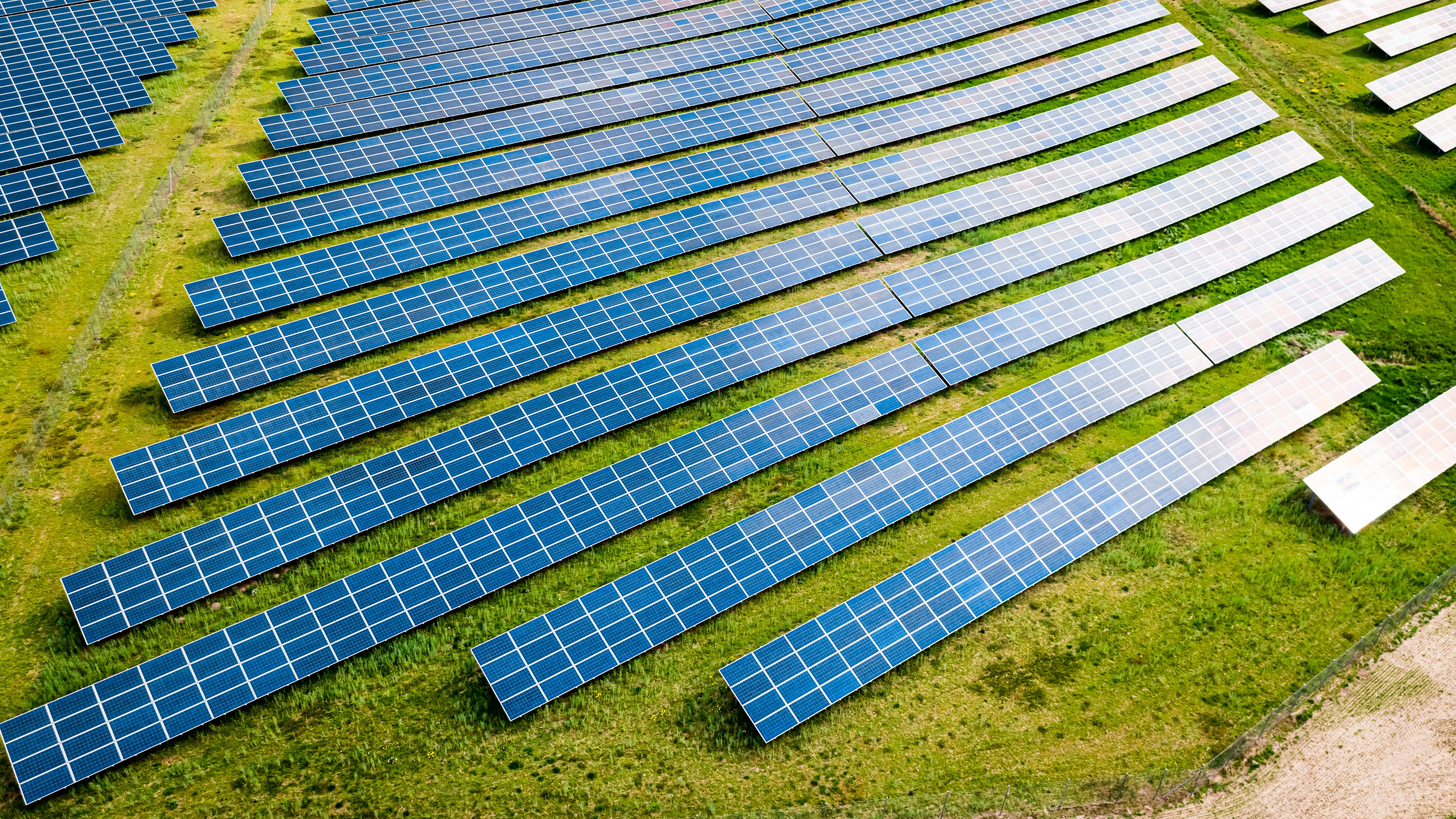 Aerial view of a solar panel array on a green field